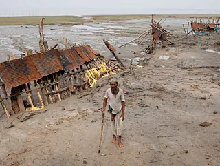 Ein Bewohner der Küste Bangladeshs vor einem zerstörten Hochwasserschutz.